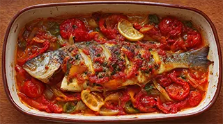 photo of a baked bass with tomato juice, tomatoes, bell pepper, green onions and lemons