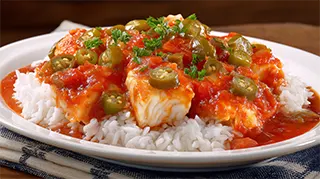 photo of cajun cod fish with a green pepper, tomato sauce over a plate of steamed rice