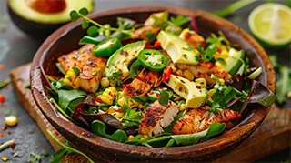 photo of a fresh catfish salad with mixed greens, diced avocado, corn kernals and jalapeno 
